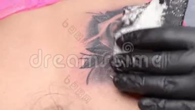 纹身艺术家在一个女人的肩膀上刺上一个纹身。特写。